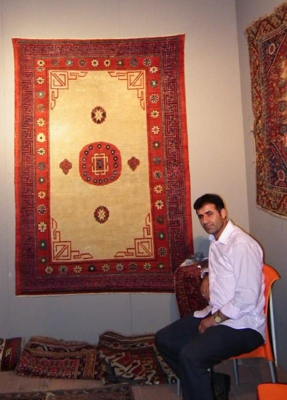 Ismail Neseli, Doga Hali, in front of a Khotan rug.